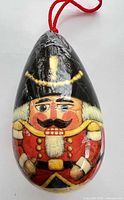Front view of egg-shaped ornament showing nutcracker design and hanging cord
