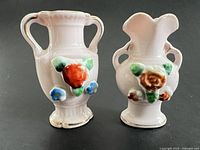 Front view of both pink miniature urn vases showing floral decorations and handles