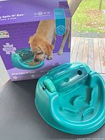 Feeder in front of original box showing product image and branding