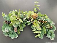 Full view of curved garland showing greenery, cones and accents