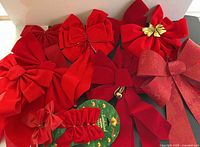 Overview of assorted red bows varying sizes on black background