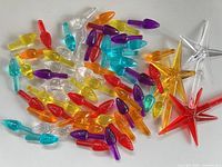 Pile of multicolour flame-shaped plastic pegs with three star toppers visible