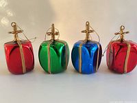 Front view of all four glass gift ornaments showing colors and gold trim
