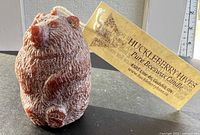 Front view of bear-shaped beeswax candle with brand tag visible