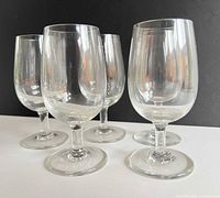 Five clear stemmed glasses grouped