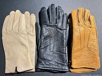 Front view three pairs beige, black, tan leather gloves