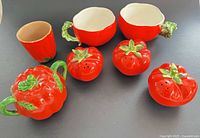 Front view of all seven tomato-pattern ceramic pieces