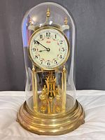 Full view of Kundo anniversary clock with glass dome and brass base