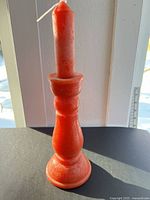 Full view of red wax candle resembling candlestick