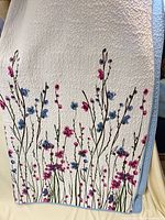 Full view of quilt showing floral front design and blue reverse edge