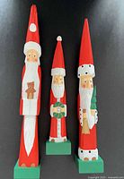 Three wooden Santa figurines side by side