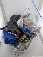 Plastic tub with zip bags containing mixed jewelry and watch parts
