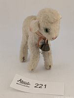Full frontal three-quarter view of Steiff Lamby plush showing tag, bell and single eye
