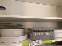 Shelf view showing boxed oval casserole, two round casseroles with lids, shallow dish