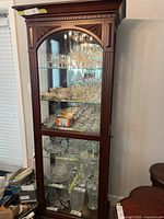 Full front view of tall wooden glass display cabinet showing shelves and contents (contents not included)