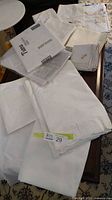 Assorted folded white tablecloths and napkins on table, including packaged piece