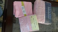 All packaged pink Texmade bedding and extra pillowcases on table