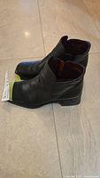 Side profile of both black leather ankle boots
