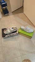 Two shoeboxes with both pairs of white sandals displayed on top