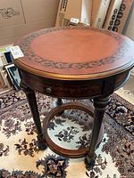 Full view of round wooden side table showing legs, stretcher, and drawer