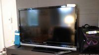 Front view of Sony Bravia TV on stand with remote visible