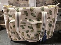 Front of cream canvas tote with green leaf pattern, tags visible
