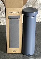 Grinder beside open box showing branding and design