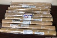 Front view of nine sealed kraft wrapping rolls with white holiday designs and gift tag pack