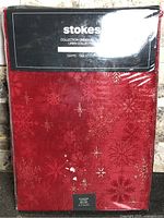 Front of packaged Stokes red snowflake tablecloth