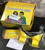 Closed retail box front and contents including goggles, card deck, notepad