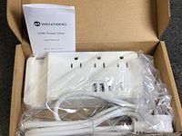 Open box showing power strip, cord, and user manual