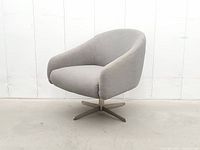 Front view of grey upholstered swivel armchair showing seat, arms and metal base