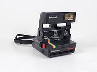 Front angled view of Polaroid Supercolor 635 CL showing lens, flash, rainbow stripe, and strap