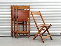Stack of four oak folding chairs folded and one chair open