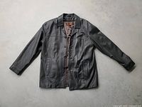 Full view of black leather jacket laid flat, showing front, sleeves, collar, and overall condition