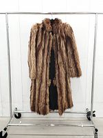 Front view of full-length brown fur coat on rack
