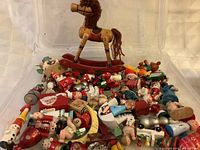 Plastic bin holding numerous small wooden Christmas figures and larger wooden rocking horse
