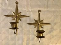 Front view of both brass starburst wall sconces showing candle cups and starburst design
