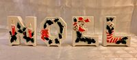Front view of four ceramic NOEL letters showing painted holly and decorations