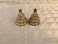 Front view of both Christmas tree shakers showing star finials and tree detailing