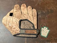 Front of tan leather glove with hang tag attached, showing overall form and felt lining