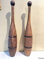 Full view of both wooden Indian clubs standing upright