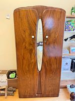 Full view of armoire front showing walnut veneer, oval mirror and knobs