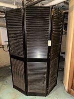 Full view of folded three-panel black louvered room divider