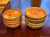 Two stacks of colorful hand painted bowls, four medium and four small