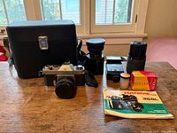 Full kit displayed including camera, two lenses, flash, close-up attachment, Portra film, manual and case