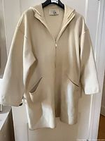 Front view of cream wool coat liner on hanger, zipped, showing overall style and condition