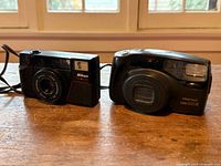 Front view of Nikon One Touch and Pentax Zoom 105-R cameras side by side