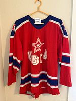 Full frontal view of red CCM CSKA Moscow hockey jersey on hanger