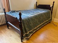Full view of assembled mahogany twin bed frame with bedding